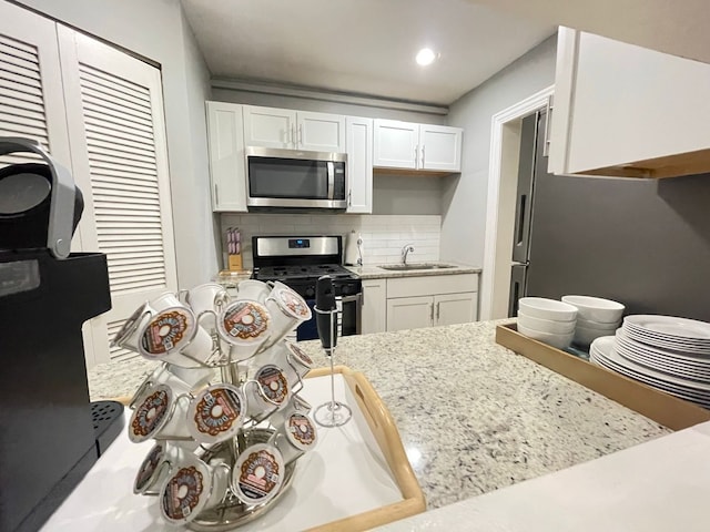 kitchen with white cabinetry, stainless steel appliances, sink, and decorative backsplash