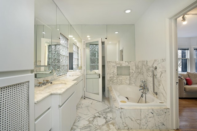 bathroom with tiled tub and vanity