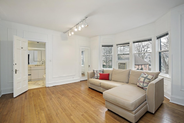 living room featuring cooling unit, rail lighting, and light wood-type flooring