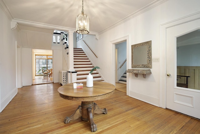 foyer with an inviting chandelier, crown molding, and light hardwood / wood-style flooring