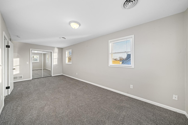 unfurnished bedroom with dark colored carpet and a closet