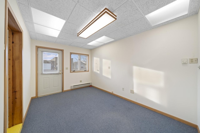 carpeted empty room with a drop ceiling and a baseboard heating unit