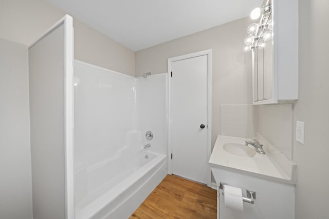 bathroom with vanity, hardwood / wood-style floors, and washtub / shower combination