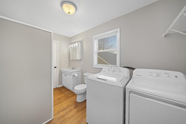 laundry area featuring washing machine and dryer, sink, and light hardwood / wood-style floors