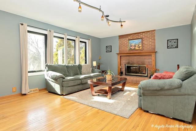 living room with a fireplace, track lighting, and light wood-type flooring