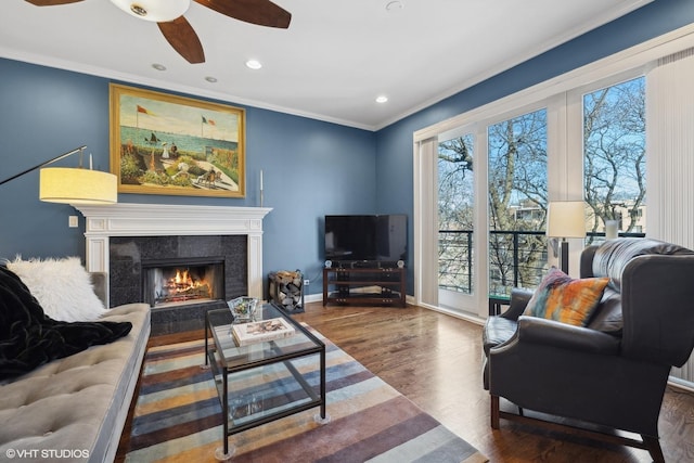 living room featuring ceiling fan, ornamental molding, dark hardwood / wood-style floors, and a high end fireplace