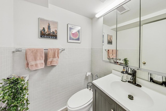 bathroom featuring vanity, tile walls, and toilet