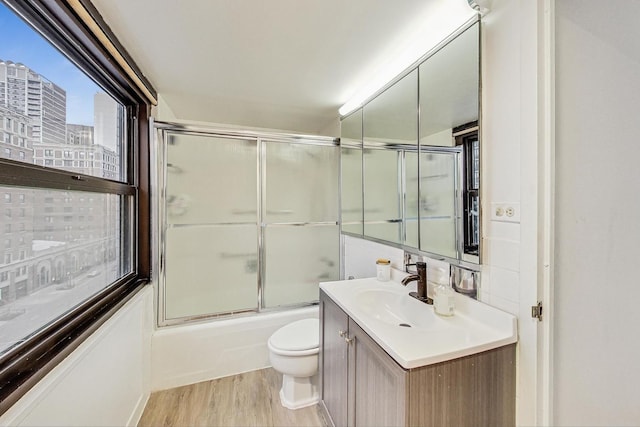 full bathroom featuring enclosed tub / shower combo, vanity, toilet, and wood-type flooring