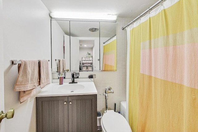 bathroom featuring vanity, tile walls, and toilet