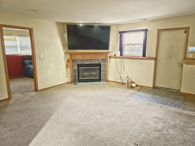 unfurnished living room featuring a tiled fireplace, carpet, and baseboards