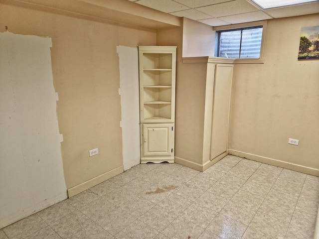 unfurnished bedroom with light floors, baseboards, and a drop ceiling