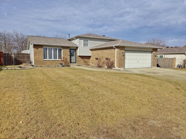 tri-level home with a front lawn, concrete driveway, an attached garage, and fence