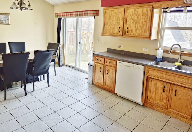 kitchen featuring light tile patterned floors, a sink, dishwasher, dark countertops, and a chandelier