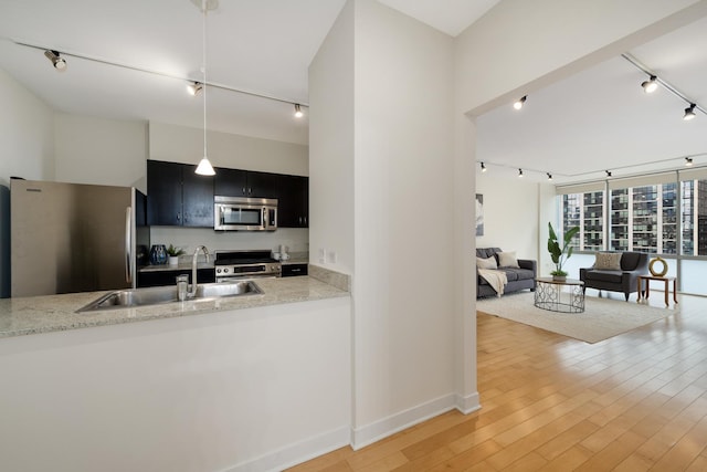 kitchen featuring sink, hardwood / wood-style flooring, appliances with stainless steel finishes, track lighting, and decorative light fixtures