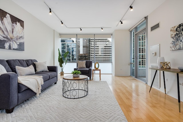 living room featuring expansive windows, rail lighting, and light hardwood / wood-style flooring