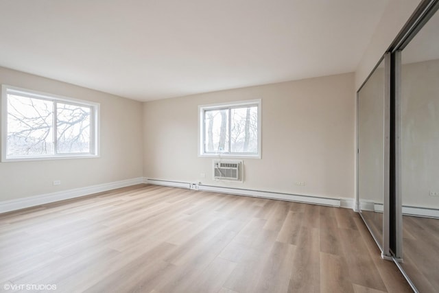 unfurnished bedroom featuring light hardwood / wood-style flooring, a wall unit AC, and a baseboard radiator