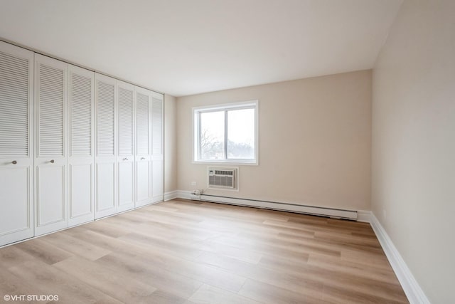 unfurnished bedroom with a baseboard heating unit, a closet, light hardwood / wood-style floors, and an AC wall unit