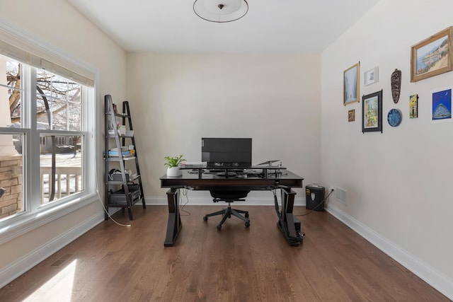 office space featuring dark wood-type flooring, a wealth of natural light, visible vents, and baseboards