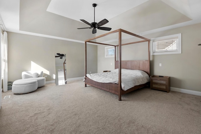 carpeted bedroom featuring a raised ceiling, a ceiling fan, and baseboards