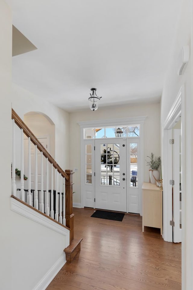 foyer entrance featuring stairway, baseboards, and wood finished floors