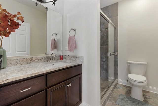 full bathroom featuring a stall shower, baseboards, vanity, and toilet