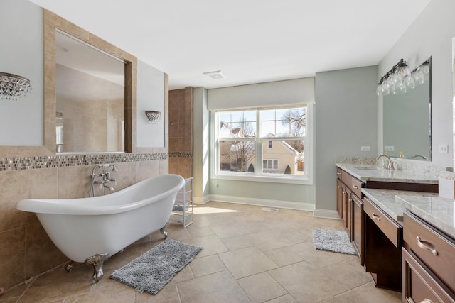 full bath with visible vents, a freestanding tub, vanity, and tile walls