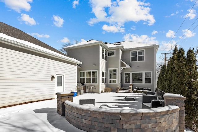 snow covered house featuring a patio area