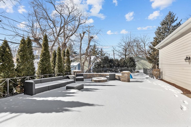 snow covered patio with an outdoor living space with a fire pit