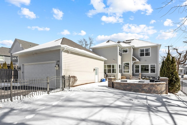 snow covered house with an attached garage and a fenced front yard