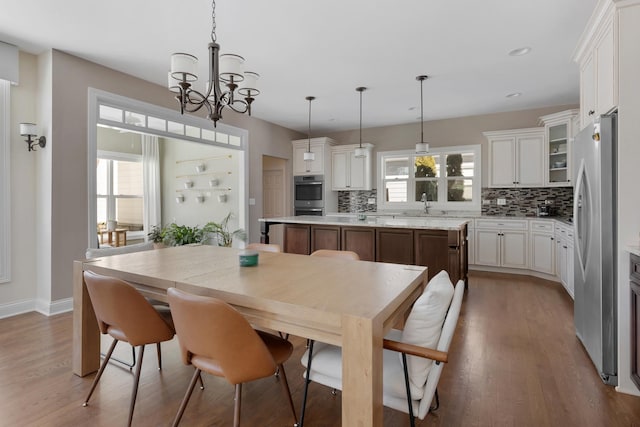 dining space with light wood finished floors, a wealth of natural light, and a notable chandelier