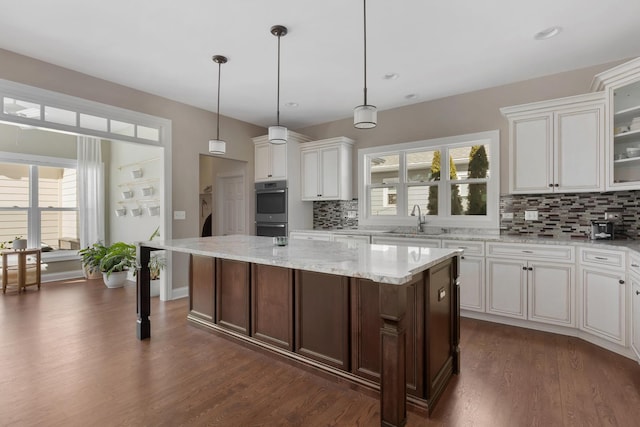 kitchen with glass insert cabinets, a sink, and a kitchen island