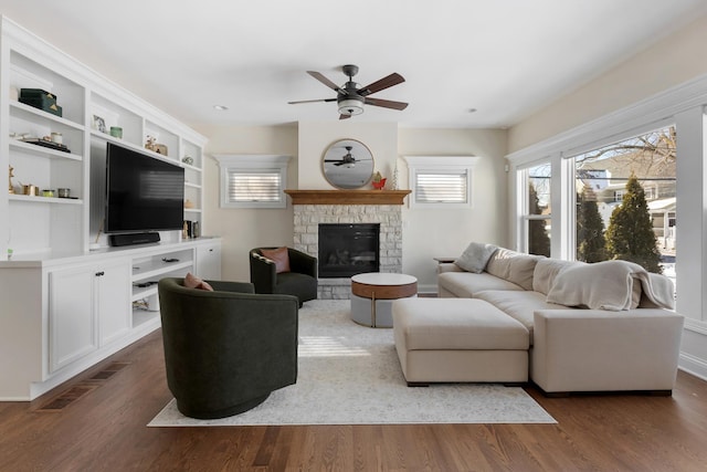 living room with visible vents, a fireplace, a ceiling fan, and dark wood-style flooring