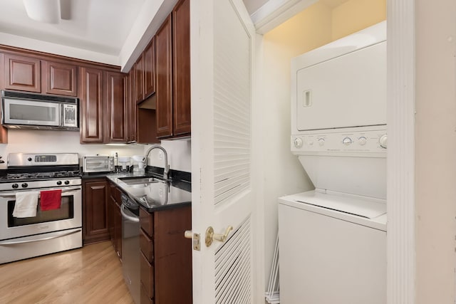 5331 S Harper Ave Unit 1, Chicago, IL 60615 - kitchen featuring stacked washer and clothes dryer, dark countertops, a sink, light wood-style floors, and appliances with stainless steel finishes