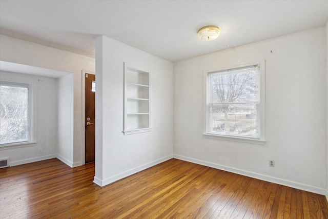 spare room with built in shelves and hardwood / wood-style floors