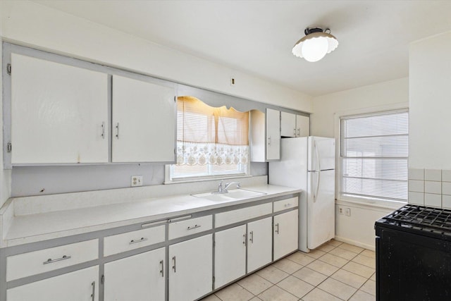 kitchen with sink, white cabinets, white refrigerator, light tile patterned floors, and gas stove