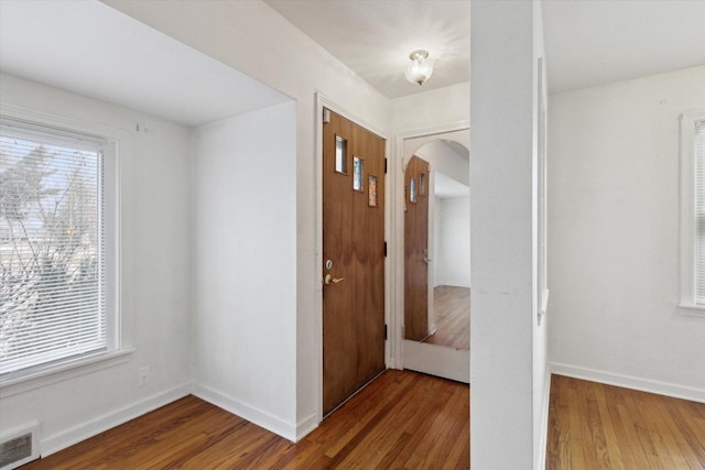 hallway with a healthy amount of sunlight and dark hardwood / wood-style floors