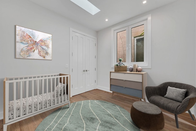 bedroom featuring hardwood / wood-style flooring, a skylight, and a closet