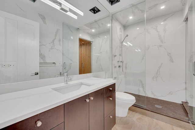 bathroom featuring a shower with door, vanity, and toilet