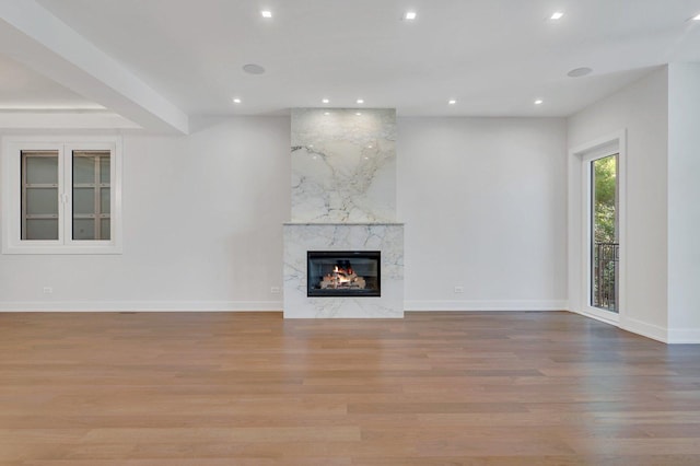 unfurnished living room featuring a premium fireplace and light hardwood / wood-style floors