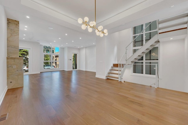 unfurnished living room with light hardwood / wood-style floors and a notable chandelier