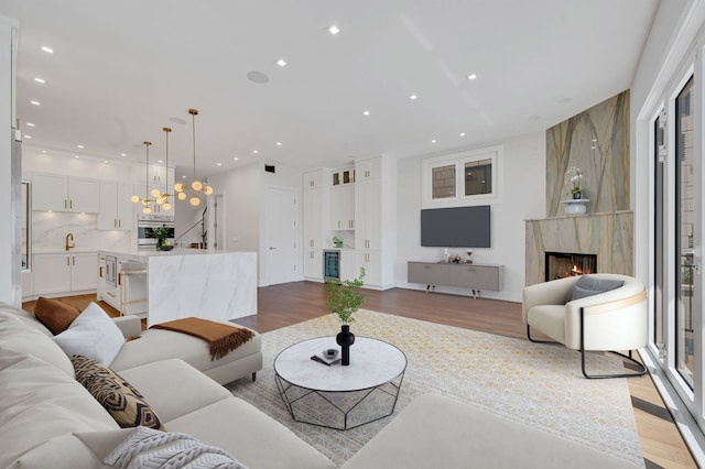 living room with beverage cooler, a fireplace, and light hardwood / wood-style floors