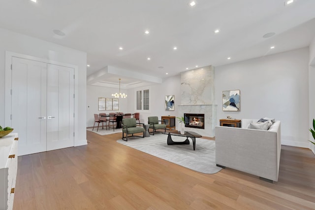 living room with a notable chandelier, light hardwood / wood-style floors, and a premium fireplace