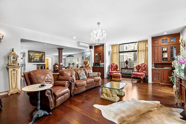 living room with decorative columns, dark hardwood / wood-style floors, a wall mounted AC, and a chandelier