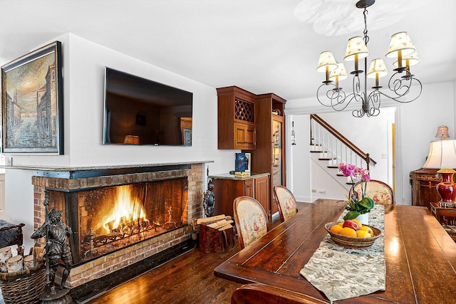 dining area featuring wood-type flooring, a notable chandelier, and a fireplace