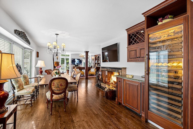 dining space featuring dark hardwood / wood-style floors, decorative columns, and a notable chandelier