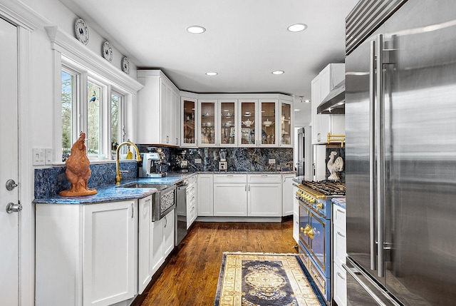 kitchen with dark stone countertops, backsplash, premium appliances, white cabinets, and dark hardwood / wood-style flooring