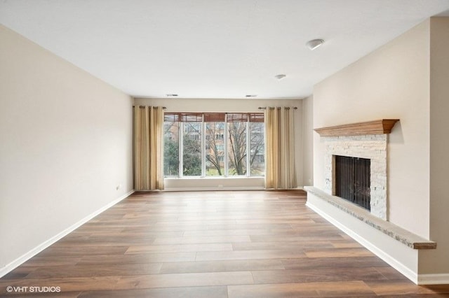 unfurnished living room with a fireplace, wood finished floors, and baseboards