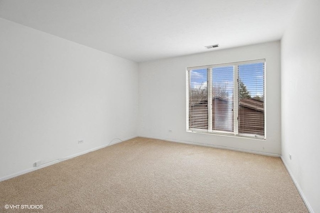 spare room with visible vents, baseboards, and light colored carpet