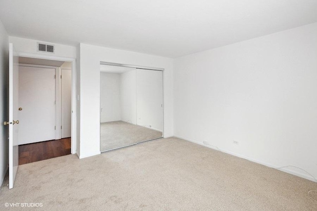 unfurnished bedroom with a closet and light carpet