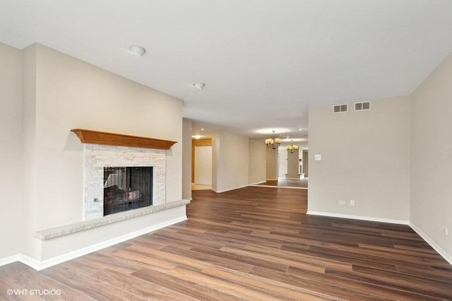 unfurnished living room featuring hardwood / wood-style flooring, a fireplace, and a chandelier